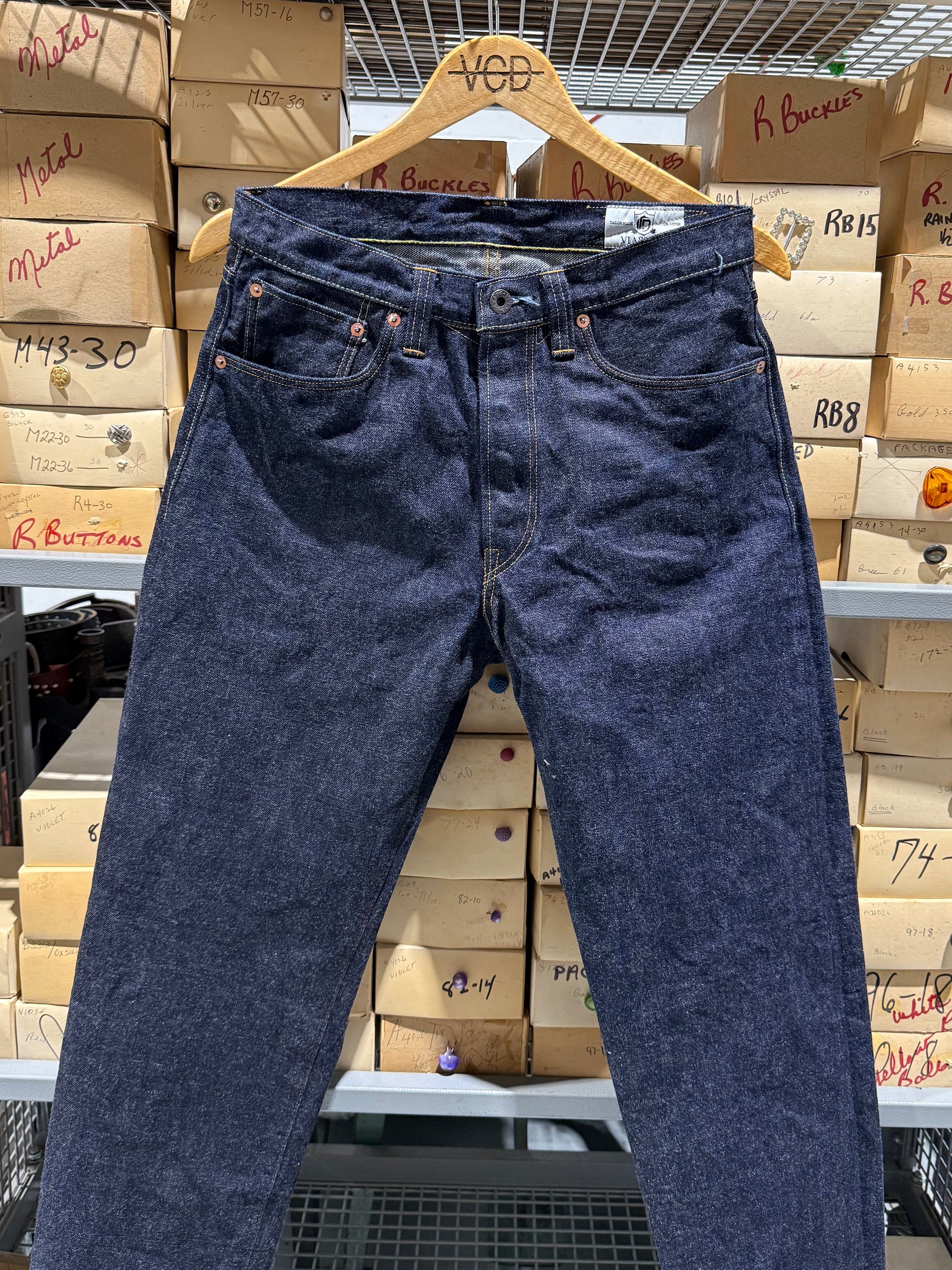 Blue jeans hanging on a rack with button boxes in the background