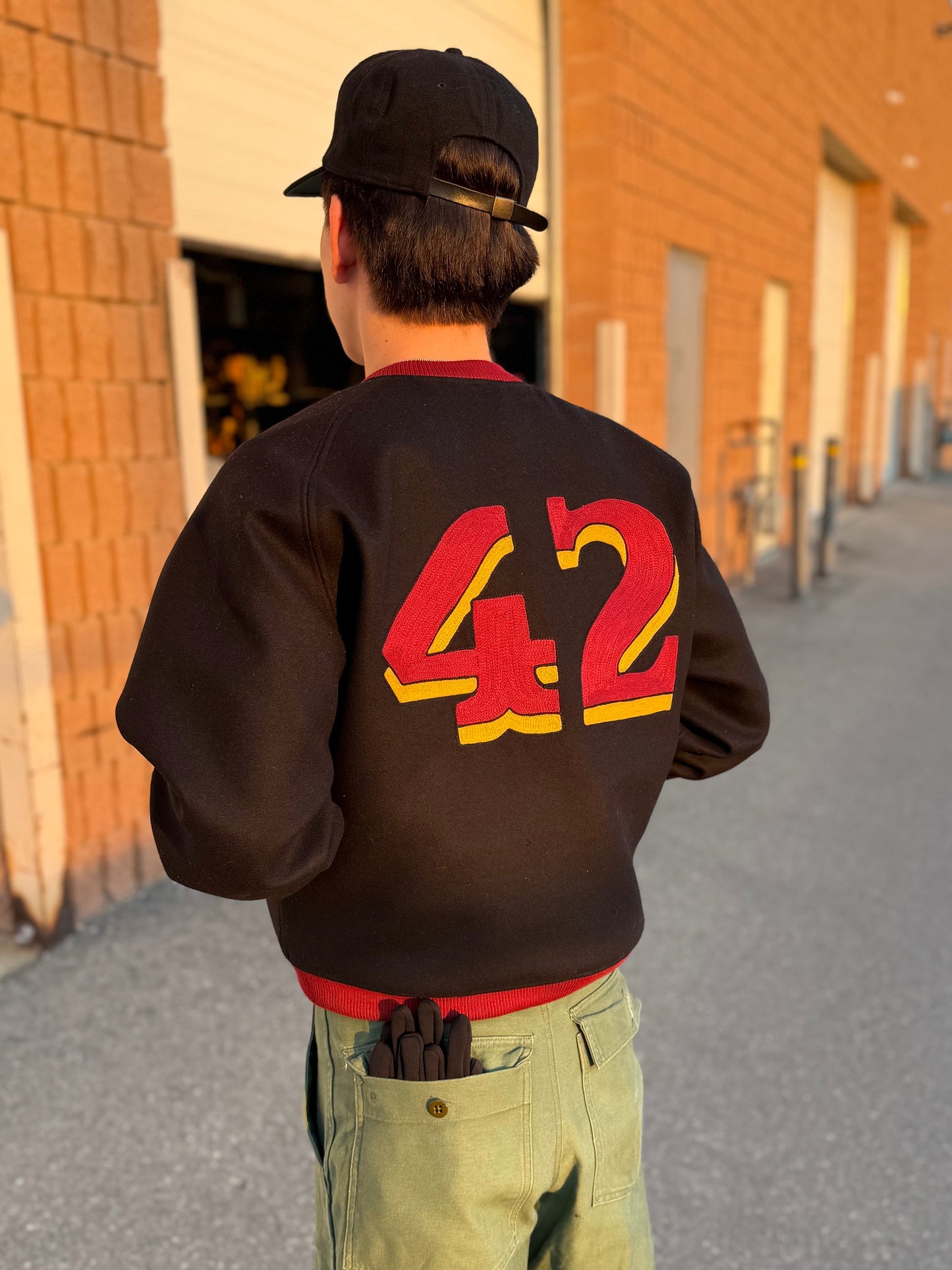 Emerson is wearing the black varsity jacket showing the 42 embroidery