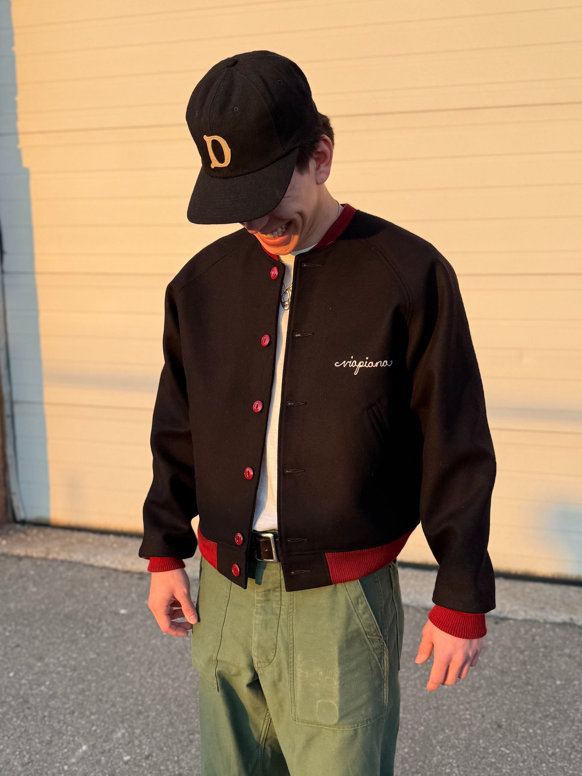 emerson is wearing the black varsity jacket with chest and back embroidery