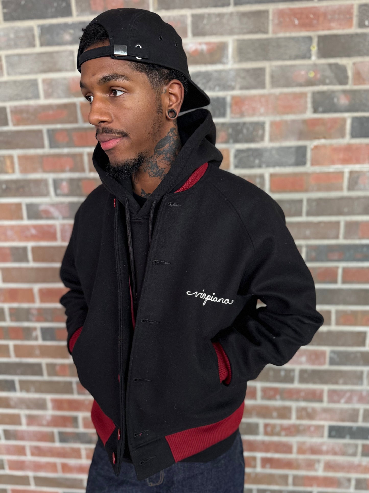 myles is wearing the black varsity jacket over a hoody to show layering 