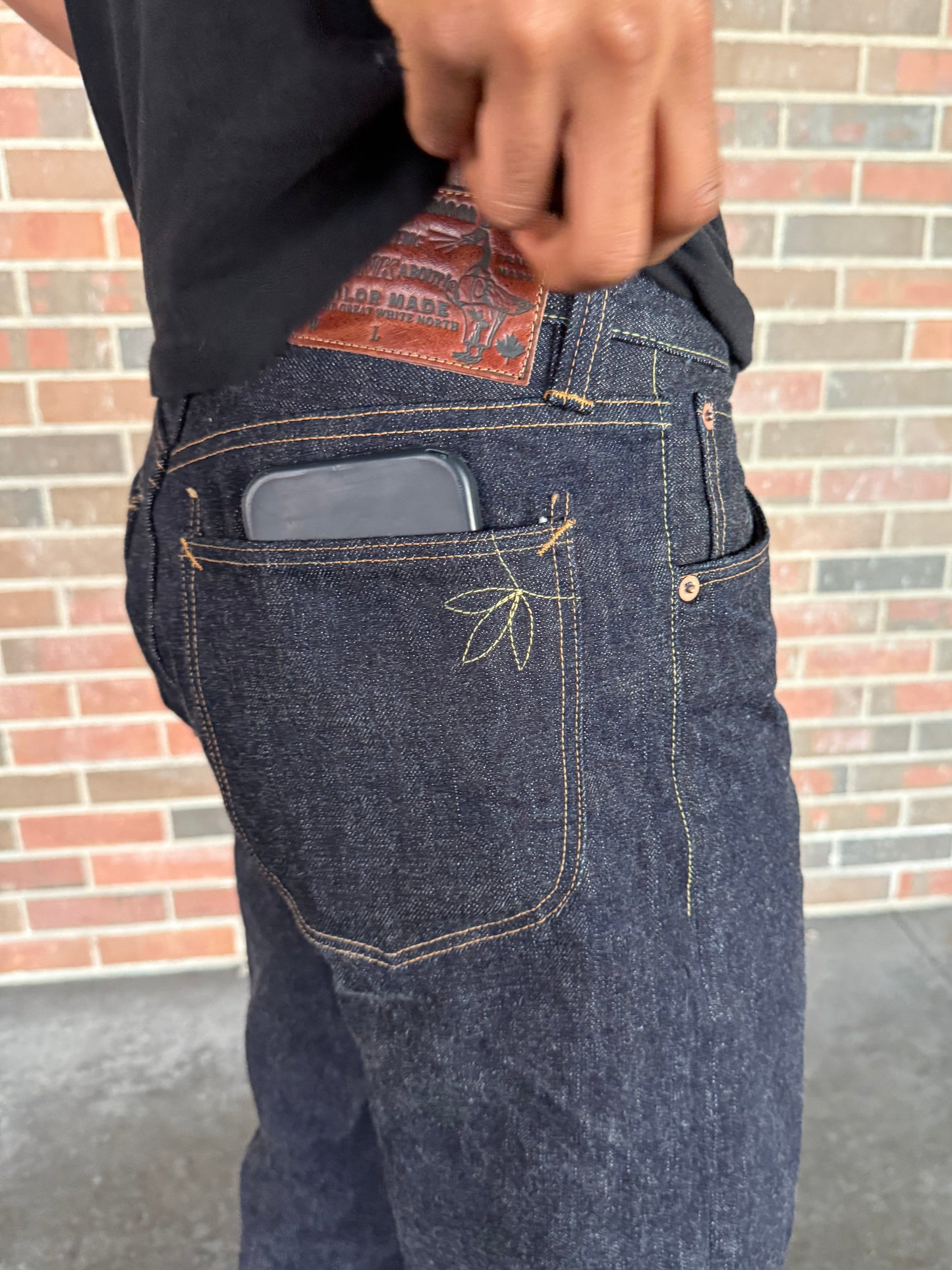 Close-up of a person wearing blue jeans with a brick wall background